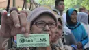 Seorang warga memperlihatkan kupon tanda pembayaran untuk beras dan daging murah, Jakarta, Minggu (21/6/2015). Operasi Pasar diluncurkan Kemendag untuk membantu warga mendapatkan beras dan daging murah saat Ramadan. (Liputan6.com/Herman Zakharia)