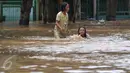 Dua anak bermain banjir di kawasan Tebet, Jakarta, Selasa (8/3/2016). Kawasan Tebet terendam banjir akibat meluapnya Sungai Ciliwung. (Liputan6.com/Gempur M Surya) 