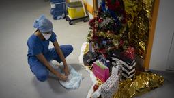 Pekerja rumah sakit Sonia Mokhtari membuat hiasan salju dari kain medis untuk pohon Natal di unit perawatan intensif COVID-19 di rumah sakit la Timone di Marseille, Prancis selatan, Jumat (24/12/2021). (AP Photo/Daniel Cole)