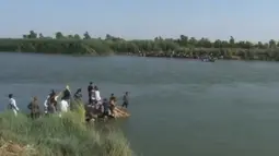 Sebuah keluarga berusaha melarikan diri dari kota Fallujah yang digempur pasukan pemerintah Irak, dengan menyebrangi Sungai Eufrat, 3 Juni 2016. ISIS kerap menggunakan ratusan keluarga di Fallujah sebagai perisai manusia dalam pertempuran. (REUTERS TV)