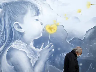 Pejalan kaki yang mengenakan masker berjalan di depan mural, di stasiun metro di Athena, Senin (15/11/2021). Pihak berwenang mengatakan kematian COVID-19 di Yunani mencapai tingkat tertinggi dalam enam bulan karena sekitar sepertiga dari populasi negara itu belum divaksinasi (AP/Thanassis Stavrakis)