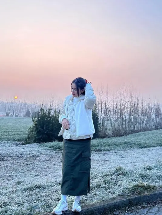 Ia memadukan turtleneck dan coat winter warna putih senada, serta rok panjang warna hijau army. [@ayutingting92].