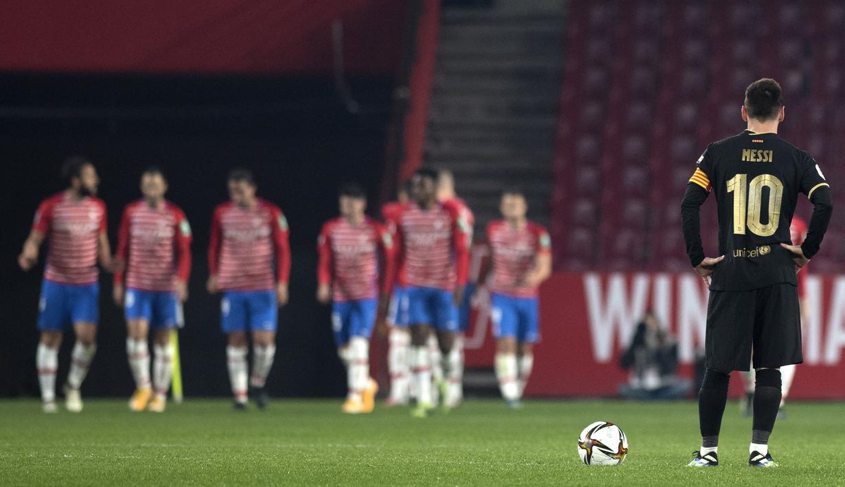 Striker Barcelona, Lionel Messi terpana saat para pemain Granada melakukan selebrasi usai mencetak gol dalam laga perempatfinal Copa del Rey 2020/21 di Nuevo Los Carmenes Stadium, Rabu (3/2/2021). Barcelona menang 5-3 (2-2) atas Granada melalui babak extra time. (AFP/Jorge Guerrero)