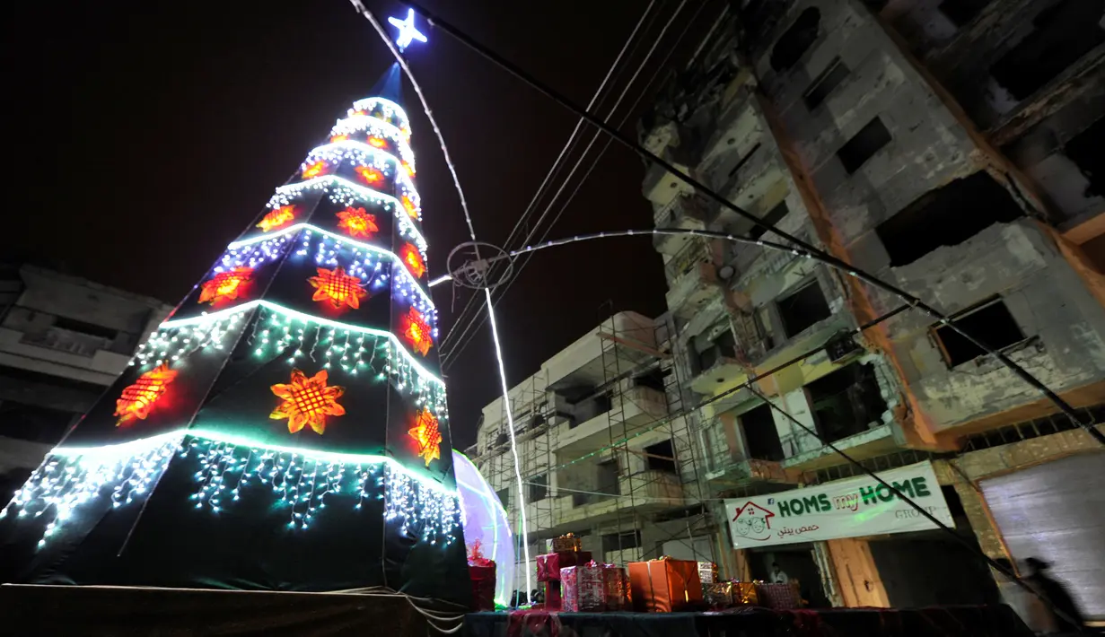 Pohon Natal berdiri di dekat bangunan yang hancur akibat serangan kelompok radikal di kawasan Al-Hamidiyah kota tua Homs, Suriah, (24/12). (REUTERS/Omar Sanadiki)