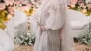Gelar mitoni untuk baby Moana, Ria Ricis tampil cantik dalam balutan dress dengan aksen cape warna pink pastel. [@forma.photograph]