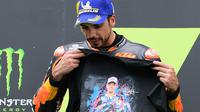 Miguel Oliveira menunjukkan baju bergambar mendiang Jason Dupasquier saat berada di podium teratas balapan MotoGP Catalunya. (LLUIS GENE / AFP)