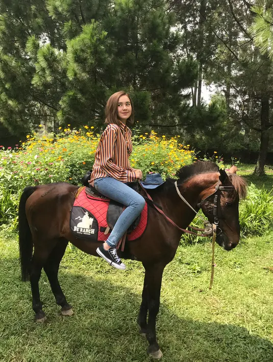 Dengan rambut pendeknya, Beby justru terlihat lebih segar dan memesona. Seperti di foto yang satu ini, saat Beby sedangmenunggangi kudanya. Beby memakai celana jeans dan kemeja garis-garis. (Instagram/bebytsabina)