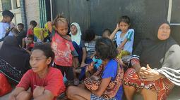 Orang-orang menunggu di luar rumah mereka setelah gempa bumi di Maumere, Indonesia, Selasa (14/12/2021). BMKG menghimbau masyarakat untuk tetap berhati-hati terhadap gempa susulan meskipun status tsunami dengan ancaman waspada telah dicabut. (AP Photo)