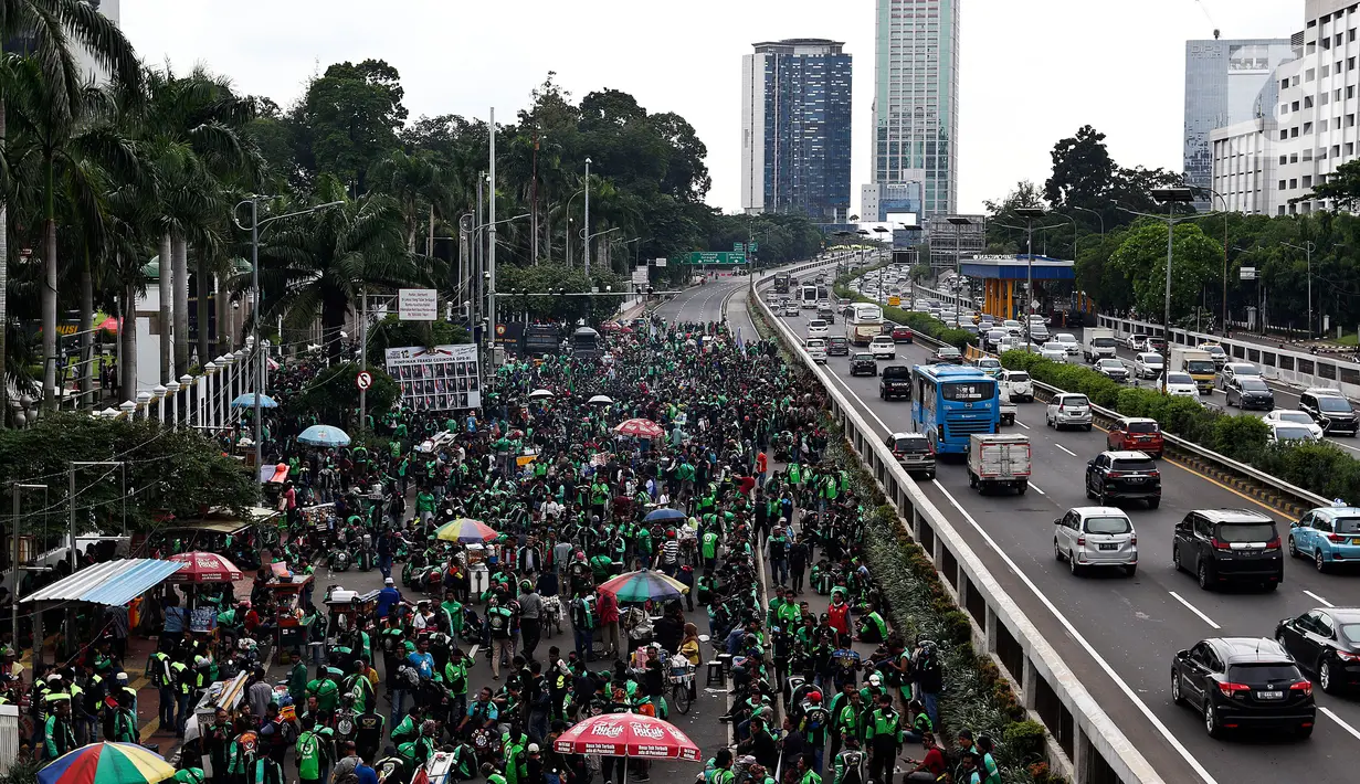 Pengemudi ojek online (ojol) menggelar demonstrasi di depan Gedung DPR/MPR, Senayan, Jakarta, Jumat (28/2/2020). Mereka menyampaikan tuntutan terkait UU No 22/2009 itu direvisi dan menjadikan kendaraan roda dua sebagai transportasi khusus terbatas. (Liputan6.com/Johan Tallo)