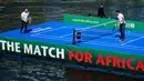 Petenis Roger Federer mengembalikan bola ke arah petenis Andy Murray pada pertandingan amal di sebuah lapangan kecil di atas sungai Kota Zurich, Senin (10/4). Pertandingan amal itu mampu menggalang dana 2 juta euro (Rp28 miliar). (Michael Buholzer/AFP)