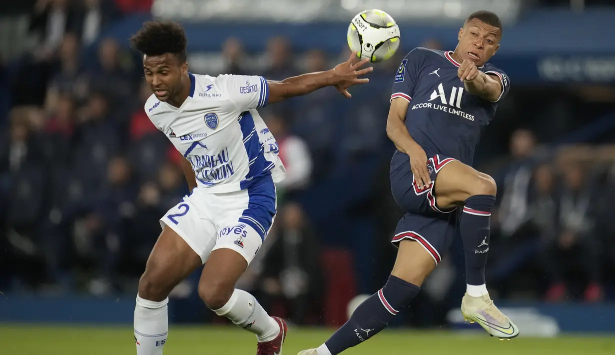 <p>Bek Troyes, Erik Ross Palmer-Brown berebut bola dengan penyerang Paris Saint Germain (PSG) Kylian Mbappe pada matchday ke-36 Ligue 1 musim 2021-22 di Parc de Princes pada laga lanjuta Ligue 1, Senin (9/5/2022) dini hari WIB. PSG harus puas meraih hasil imbang 2-2 saat menjamu klub papan bawah, Troyes. (AP Photo/Christophe Ena)</p>