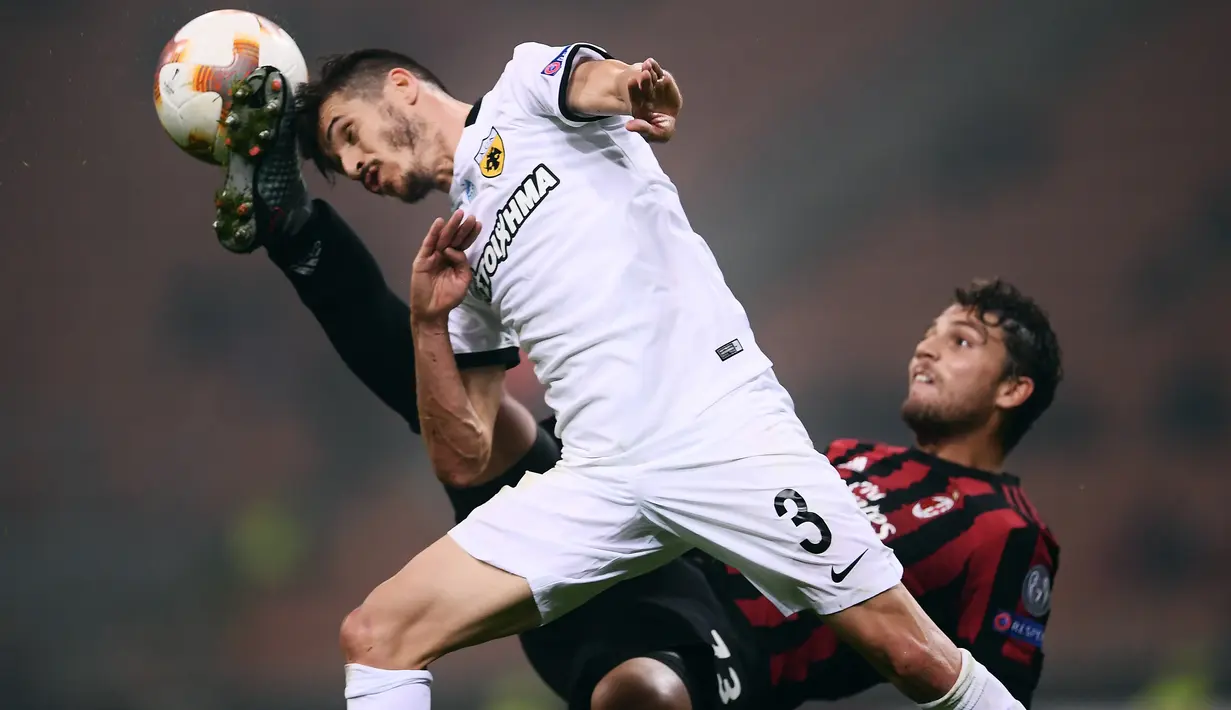 Bek AEK Athens, Helder Lopes melompat merebut bola dari gelandang AC Milan, Manuel Locatelli pada pertandingan Grup D Liga Europa di San Siro, Kamis (19/10). AEK Athens menambah kekecewaan AC Milan setelah hanya bermain tanpa gol. (MARCO BERTORELLO/AFP)