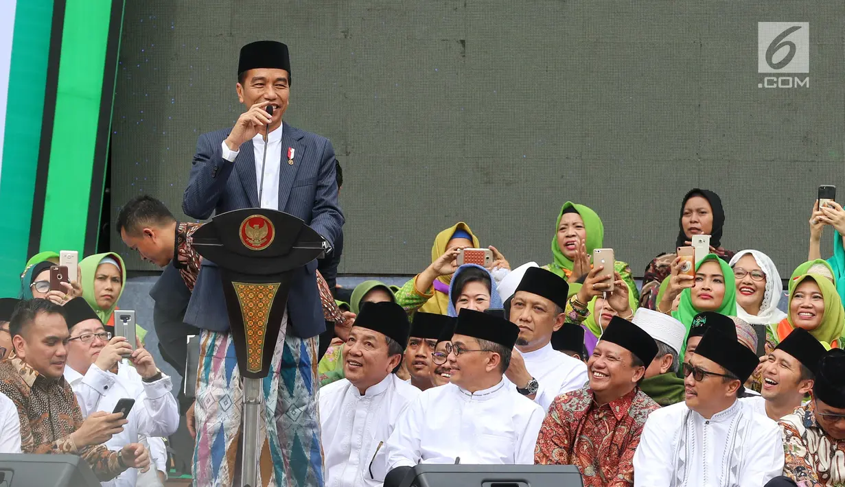 Presiden Joko Widodo atau Jokowi memberi sambutan dalam Harlah ke-73 Muslimat NU di SUGBK, Jakarta, Minggu (27/1). Jokowi datang dengan mengenakan kain sarung, jas, dan kopiah hitam. (Liputan6.com/Johan Tallo)