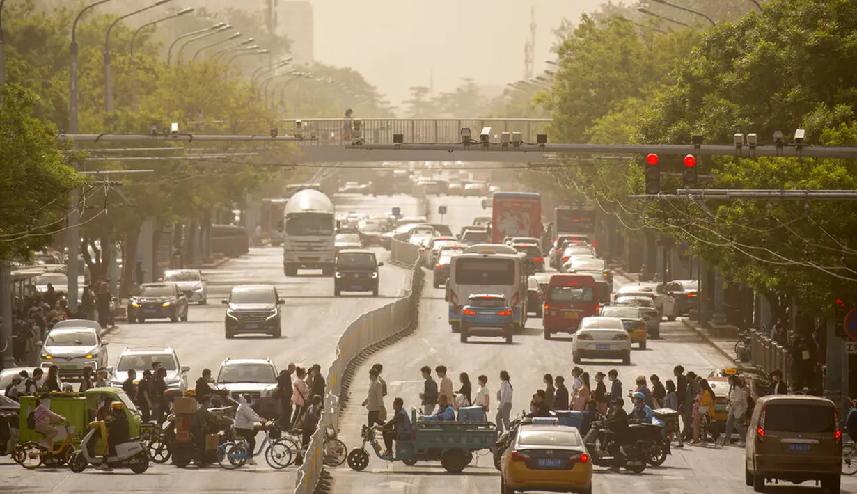 Orang-orang berjalan melintasi persimpangan saat badai pasir di Beijing, China, Kamis (6/5/2021). Debu dan badai pasir akhir musim semi mengirim indeks kualitas udara melonjak di Ibu Kota China pada hari ini. (AP Photo/Mark Schiefelbein)