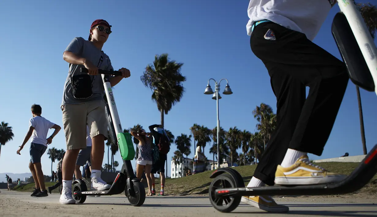 Pengendara menaiki skuter listrik dari startup LimeBike di sepanjang Venice Beach, Los Angeles, 13 Agustus 2018. Kota besar masih berjuang mengurangi kendaraan pribadi di jalan, tapi tidak pernah mendapatkan solusi tepat. (Mario Tama/Getty Images/AFP)