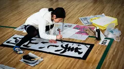 Seorang peserta menulis tulisan Jepang saat mengikuti lomba kaligrafi Tokyo, Jepang (5/1). Lomba yang digelar setiap tahun ini diikuti ribuan peserta. (AFP Photo/Behrouz Mehri)