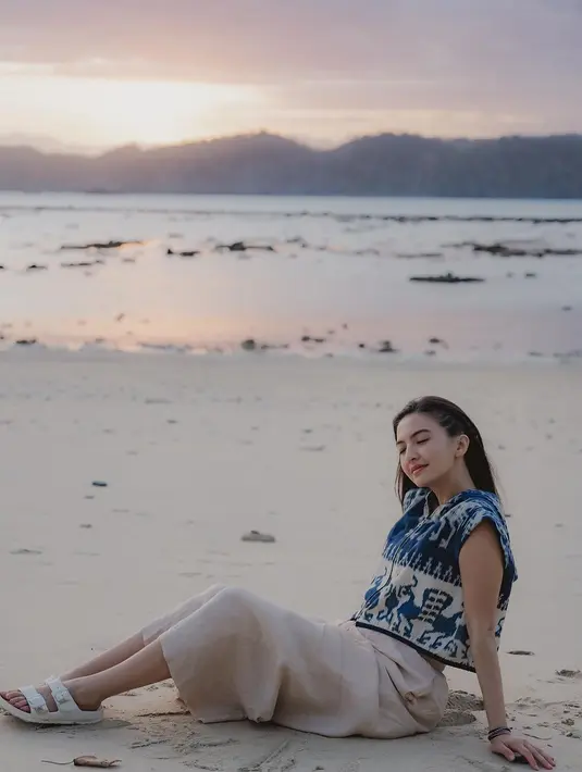 Ia padukan rompi tenun Sumba itu dengan kulot linen warna beige dan sandal putih [@ralineshah]