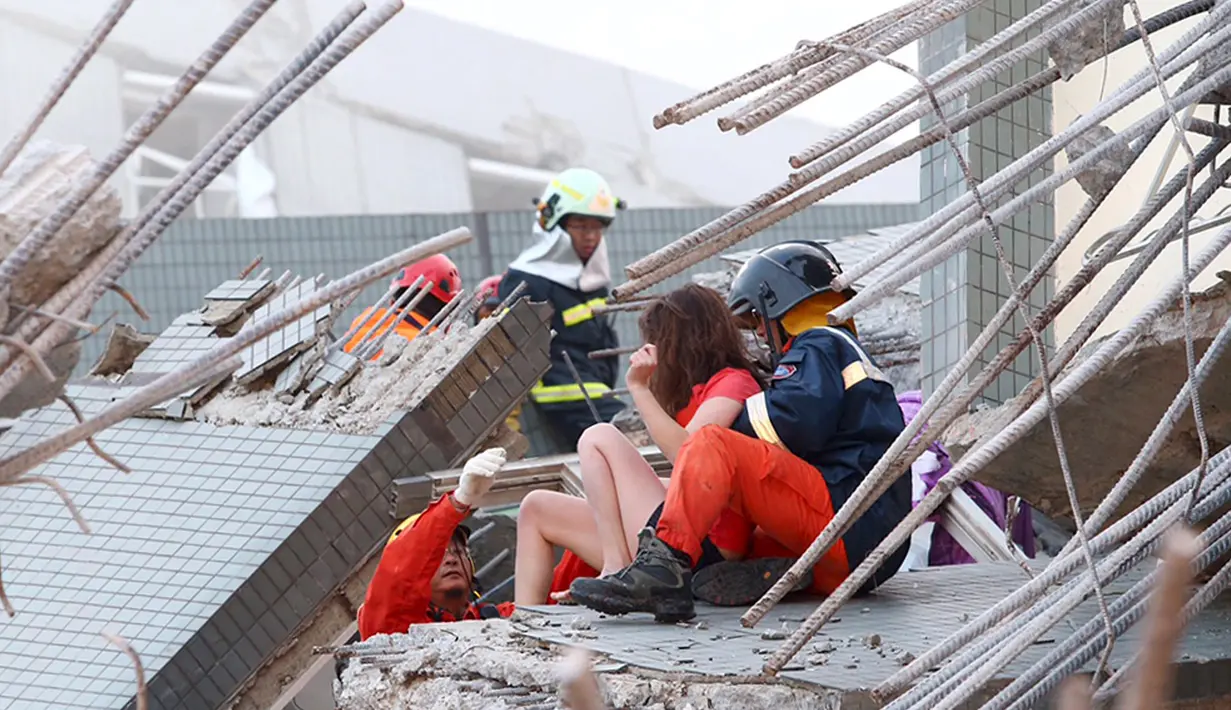 Petugas penyelamat membantu wanita di gedung apertemen yang runtuh akibat gempa 6,4 SR  di Tainan, (6/2). Menurut data meteorologi gempa terjadi pada kedalaman 16,7 kilometer di bawah permukaan laut. (REUTERS/Stringer)