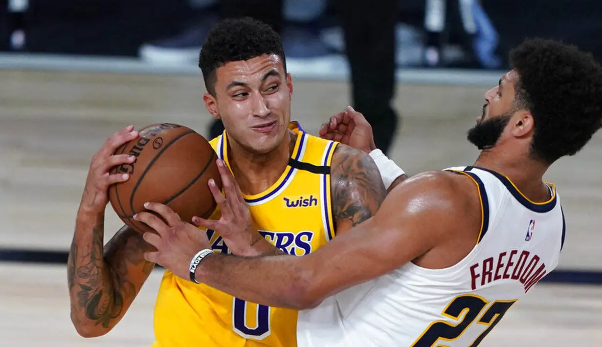 Pebasket Los Angeles Lakers, Kyle Kuzma, berusaha melewati pemain Denver Nuggets, Jamal Murray, pada laga NBA di The Arena, Senin (11/8/2020). LA Lakers menang dengan skor 124-121. (AP Photo/Ashley Landis, Pool)
