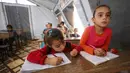 Anak-anak Suriah yang terlantar mengamati penjelasan guru saat mengikuti kegiatan belajar di dalam tenda yang diubah menjadi ruang kelas di kamp pengungsi di kota Maarrat Misrin di Provinsi Idlib, Suriah (6/10/2020). (AFP/Omar Haj Kadour)