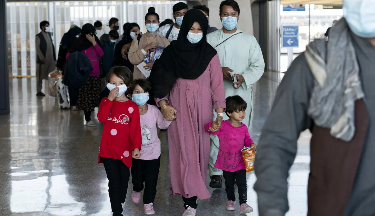 Keluarga dievakuasi dari Kabul, Afghanistan, berjalan melalui terminal sebelum naik bus setelah mereka tiba di Bandara Internasional Washington Dulles, di Chantilly, Va, Rabu (25/8/2021). (AP Photo/Jose Luis Magana)