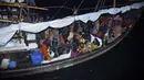 Pengungsi Rohingya duduk di perahu saat tiba di Pelabuhan Krueng Geukueh di Aceh Utara, Jumat pagi (31/12/2021). Sedikitnya 120 orang etnis Rohingya yang sempat terombang-ambing di lautan selama beberapa hari akhirnya dievakuasi ke daratan Aceh. (AP Photo/Rahmat Mirza)