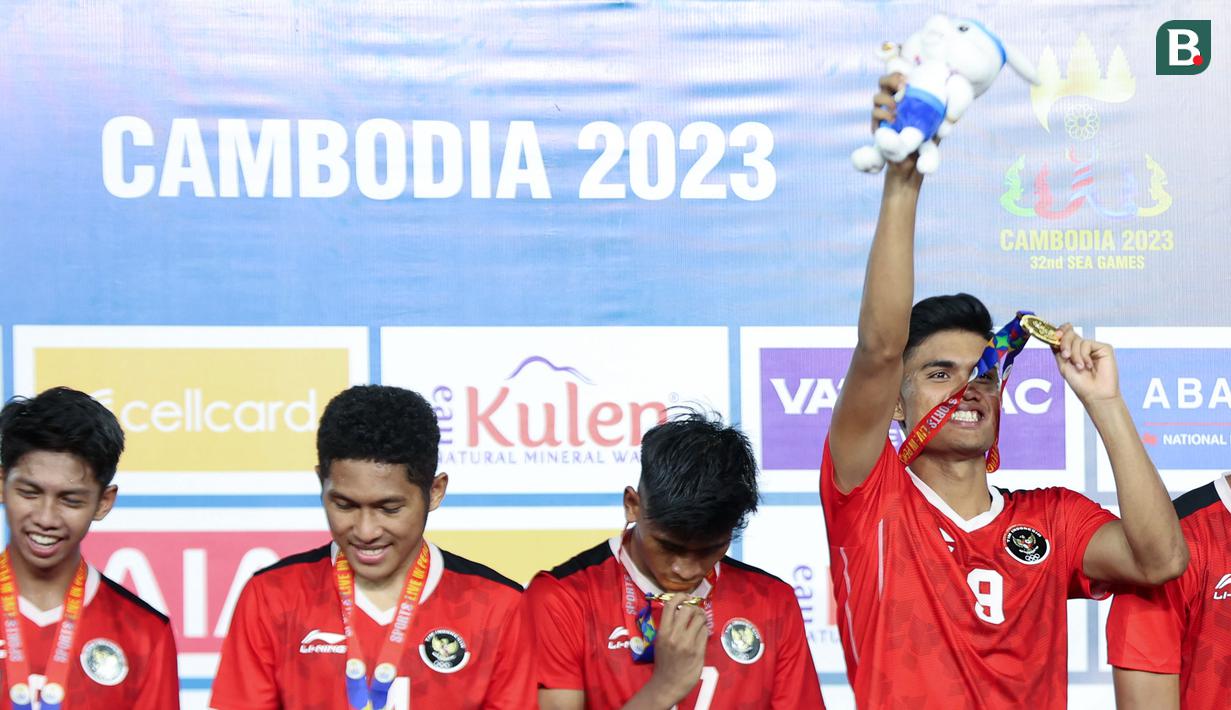 Pemain dan ofisial Timnas Indonesia U-22, Ramadhan Sananta (kanan) mengangkat medali emas dan bonekanya di atas podium saat memenangkan laga final sepak bola SEA Games 2023 melawan Thailand di Olympic Stadium, Phnom Penh, Kamboja, Selasa (16/05/2023). (AFP/Mohd Rasfan)