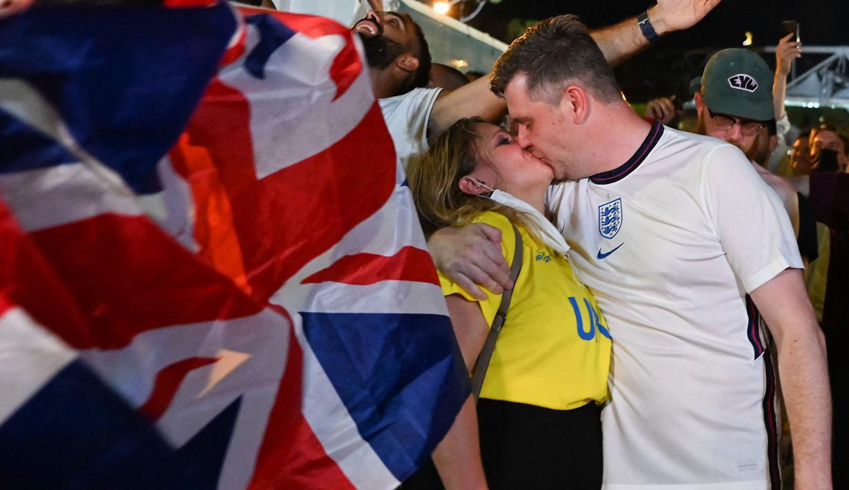 Suporter berbaju Inggris dan Ukraina berciuman saat merayakan kemenangan Timnas Inggris pada akhir pertandingan sepak bola Perempatfinal EURO 2020 antara Inggris melawan Ukraina, di depan Stadion Olimpiade, Roma pada 3 Juli 2021.
(AFP/Andreas Solaro)