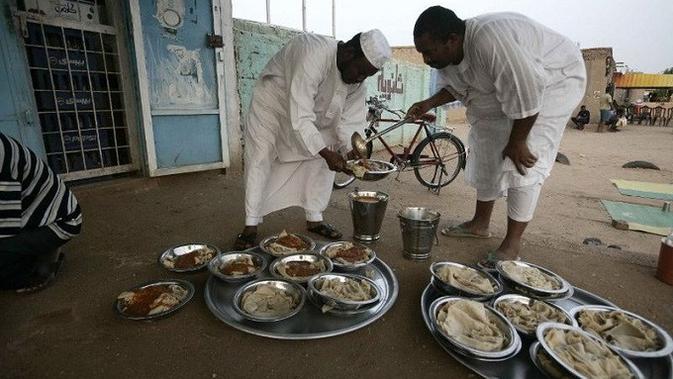 Beberapa warga Sudan terlihat sedang menyiapkan makanan sebelum makan malam Iftar di pinggir jalan raya Khartoum di desa al-Nuba (AFP)