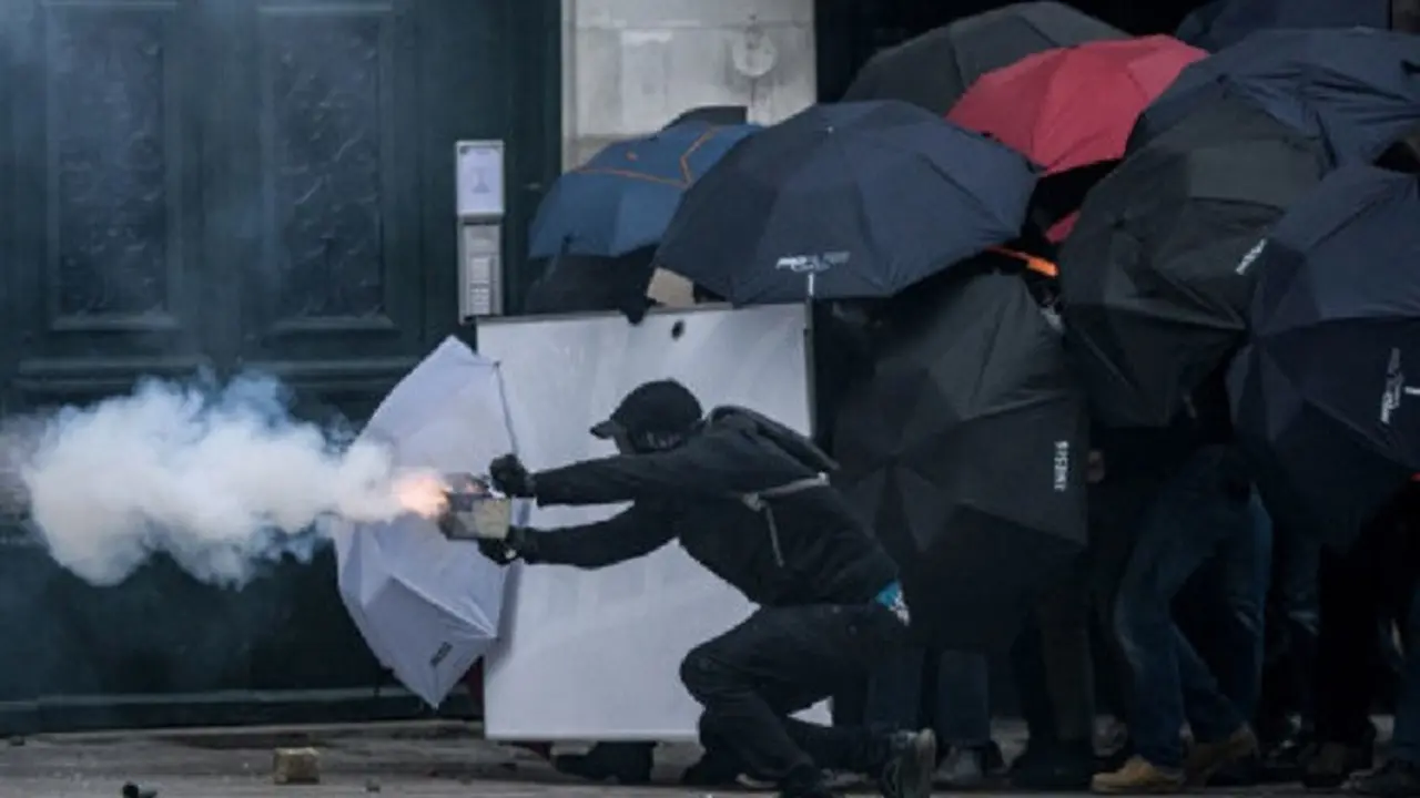Seorang pengunjuk rasa menembakkan kembang api saat bentrok dengan polisi anti huru hara selama demonstrasi pada Hari Buruh Internasional, di Nantes, Prancis, pada Senin (1/5/2023). (Dok. AFP/Loic Venance)