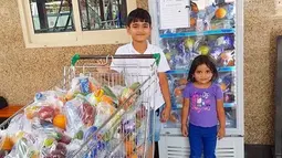 Dua orang anak berfoto di depan kulkas dan trolli yang berisi makanan dan minuman jelang bulan Ramadan di Dubai. Makanan dan minuman untuk berbuka puasa ini disediakan gratis untuk pekerja dan buruh. (www.instagram.com/ramadanfridgesdxb)