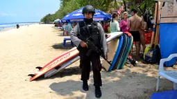 Petugas dengan senjata laras panjang dan rompi antipeluru berjaga di Pantai Kuta, Denpasar, Rabu (20/1). Polisi Indonesia mengumumkan bahwa mereka telah menangkap seorang pria yang membiayai serangan Jakarta mematikan. (AFP PHOTO/SONNY TUMBELAKA)