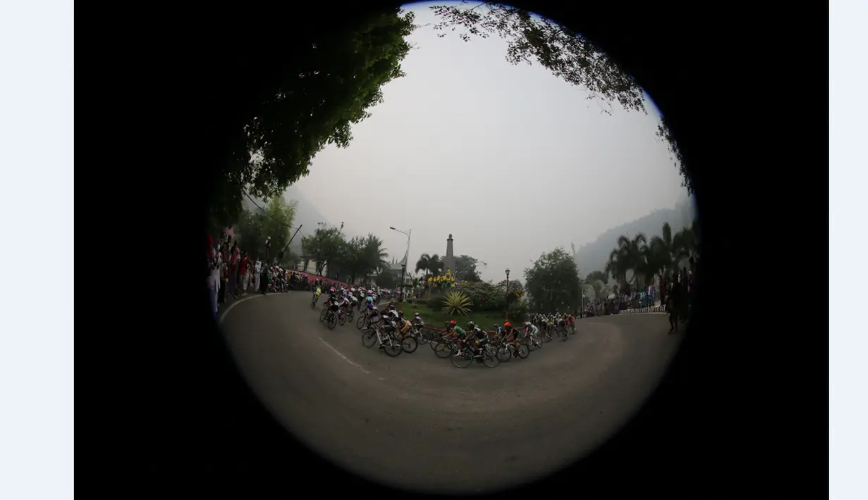 Para pebalap sepeda saat melewati sebuah tugu di kota Sawahlunto dalam Etape 4 Tour de Singkarak 2015, Selasa (6/10/2015). (Bola.com/Arief Bagus)