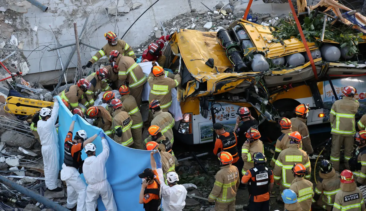 Tim SAR mencari korban di antara puing-puing bangunan yang runtuh di Gwangju, Korea Selatan (9/6/2021). Puing bangunan itu tampak jatuh dan mengubur sebagian ruas jalan. (AFP/Yonhap)