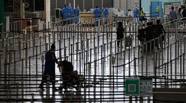 Penumpang mengantre di ruang kedatangan bus menuju hotel karantina dari bandara internasional Hong Kong di Hong Kong, Jumat (23/9/2022). Pemimpin Hong Kong  akan menghapus kebijakan karantina Covid-19 di hotel untuk semua pengunjung kota itu ketika Hong Kong u berusaha untuk membuka diri secara global setelah hampir dua tahun. (AP Photo/Lam Yik)