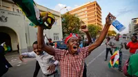 Warga Zimbabwe merayakan kabar Presiden Robert Mugabe mengundurkan diri di luar gedung parlemen, pusat kota Harare, Selasa (21/11). Surat pengunduran diri Mugabe yang dibacakan di parlemen itu mendapat sambutan sorak-sorai dan tarian. (AP/Ben Curtis)