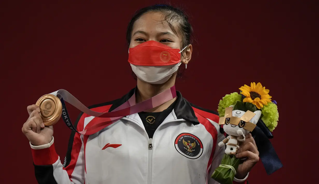 Lifter putri Indonesia Windy Cantika Aisah menunjukkan medali perunggu Olimpiade Tokyo 2020 cabang angkat besi nomor 49 kg di Tokyo International Forum, Sabtu (24/7/2021). Windy Cantika mempersembahkan medali pertama bagi Indonesia yakni perunggu dengan total angkatan 194 Kg. (AP Photo/Luca Bruno)