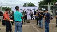 Sejumlah warga memblokir dan memasang banner bertuliskan lockdown di gerbang utama pintu masuk PT Trans Pacific Petrochemical Indotama (TPPI). (Ahmad Adiri/Liputan6.com)