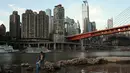 Seorang pemancing mengarungi air setelah memancing di Sungai Jialing, anak Sungai Yangtze, di Kota Chongqing, China, Rabu (24/8/2022). Sungai Yangtze telah mencapai level air terendah, dengan seluruh bagian dan lusinan anak sungai mengering. (Noel Celis/AFP)