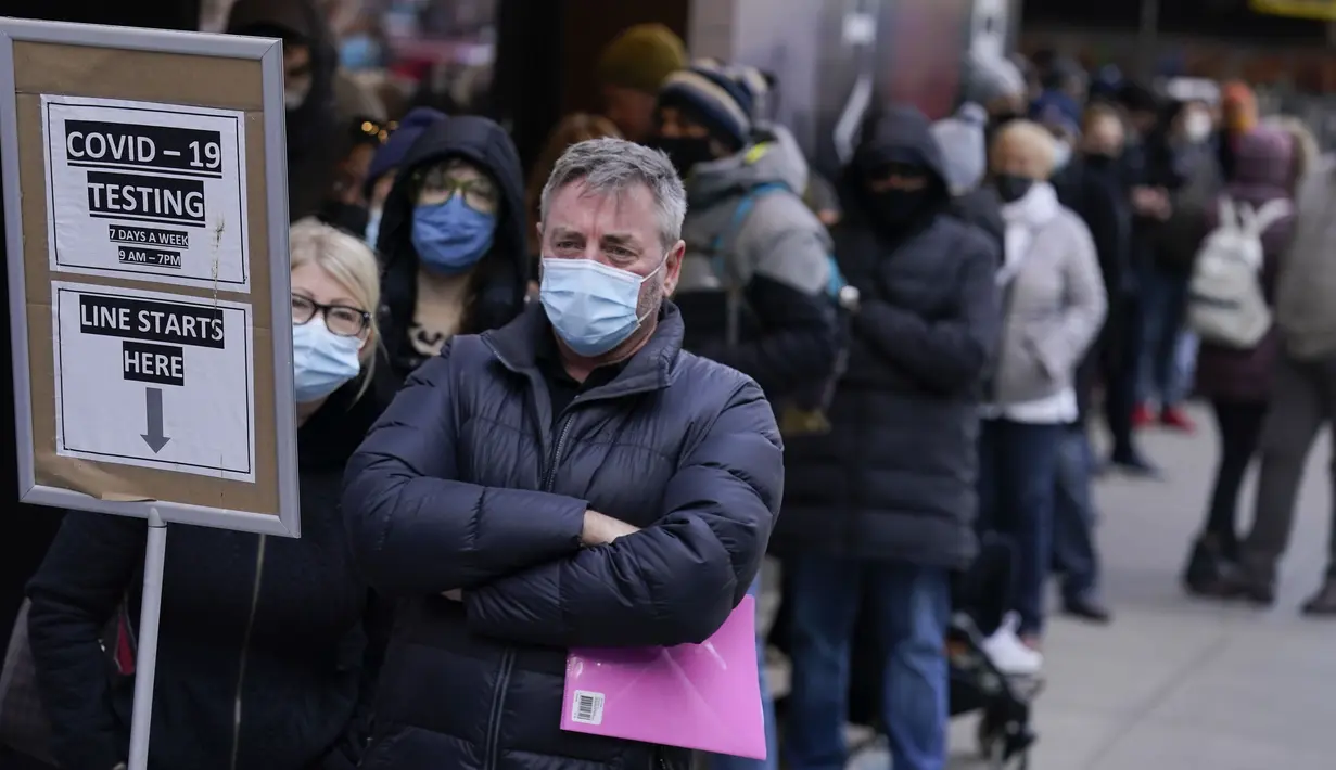 Orang-orang mengantre di tempat pengujian COVID-19 di Times Square, New York, Senin (13/12/2021). Wajib masker di semua tempat umum dalam ruangan di negara bagian New York mulai berlaku pada Senin ketika para pejabat menghadapi lonjakan kasus COVID-19 dan rawat inap. (AP Photo/Seth Wenig)