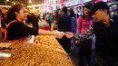 Seorang pria mencicipi makanan ringan saat berbelanja persiapan Tahun Baru Imlek di pasar Dihua Street di Taipei, Selasa (29/1). Warga Taiwan mulai berburu makanan lezat, kue kering dan barang- lainnya di pasar menjelang Imlek. (AP/Chiang Ying-ying)