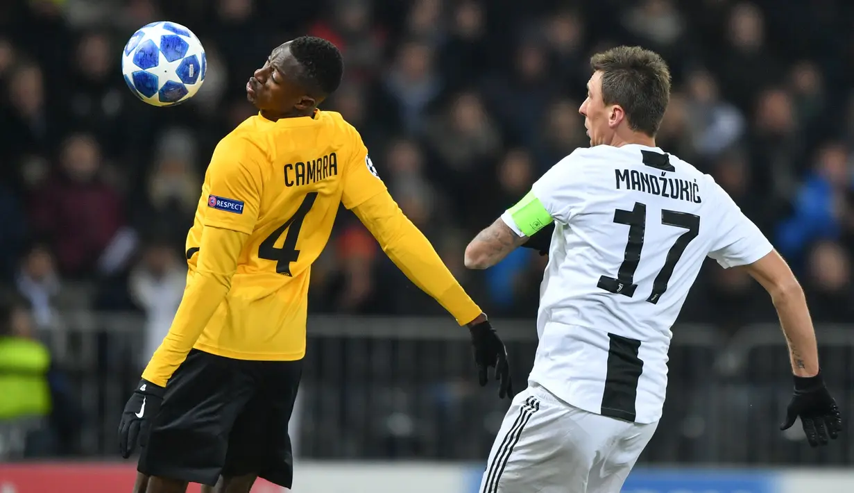 Pemain Juventus, Douglas Costa berebut bola dengan pemain Young Boys, Nicolas Moumi Ngamaleu pada laga pamungkas Grup H Liga Champions di Stade de Suisse, Kamis (13/12). Kalah 1-2, Juventus tetap keluar sebagai juara Grup H. (Fabrice COFFRINI/AFP)