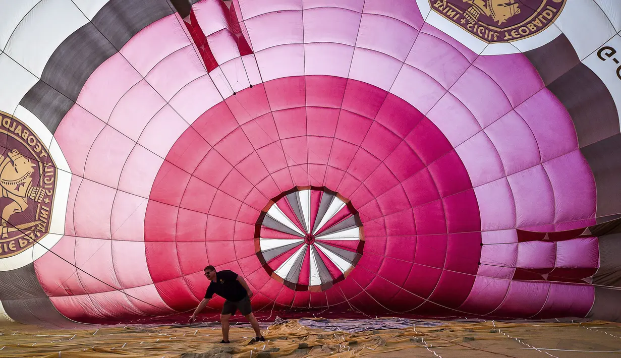 Seorang pilot memeriksa balon udara selama festival tahunan balon udara panas Bristol di Bristol, Inggris (8/8/2019). Festival balon udara ini diadakan selama empat hari dari 8-11 Agustus 2019. (Ben Birchall/PA via AP)