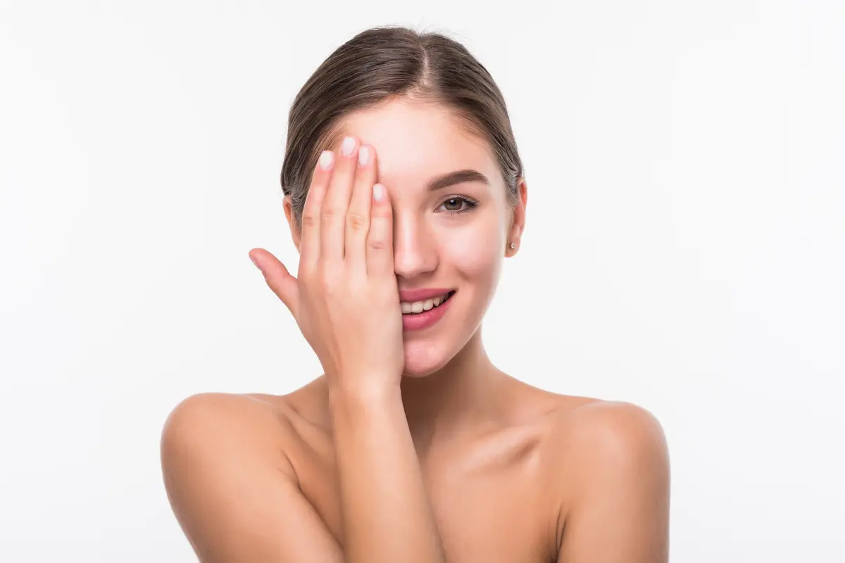 Seorang perempuan dengan rambut digulung tersenyum sambil menutup sebagian wajahnya dengan tangan (Foto Dok: Freepik/diana.grytsku)