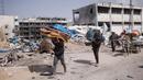 Warga Palestina membawa barang-barang mereka setelah mengunjungi rumah mereka yang hancur akibat serangan Israel di Khan Younis, Jalur Gaza, Rabu, 6 Maret 2024. (AP Photo/Mohammed Dahman)