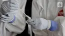 Petugas medis memasukkan hasil tes swab salah satu pedagang ke dalam tabung di Pasar Kramat Jati, Jakarta, Rabu (17/6/2020). Ratusan pedagang Pasar Kramat Jati menjalani tes swab secara bertahap sebagai upaya pemerintah memutus rantai penyebaran virus Covid-19. (merdeka.com/Iqbal S. Nugroho)