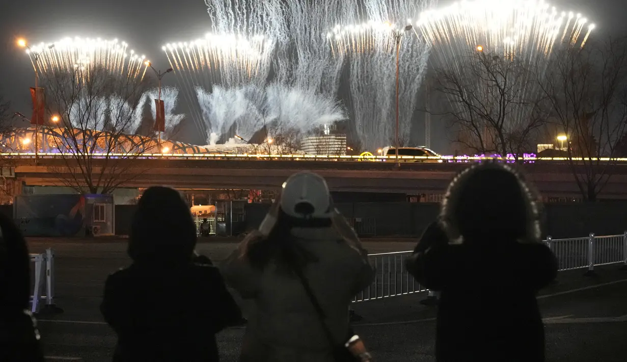 Sejumlah warga melihat kembang api dari jauh saat upacara penutupan Olimpiade Musim Dingin 2022, di Stadion Nasional, Beijing, China, Minggu (20/2/2022). (AP Photo/Natacha Pisarenko)