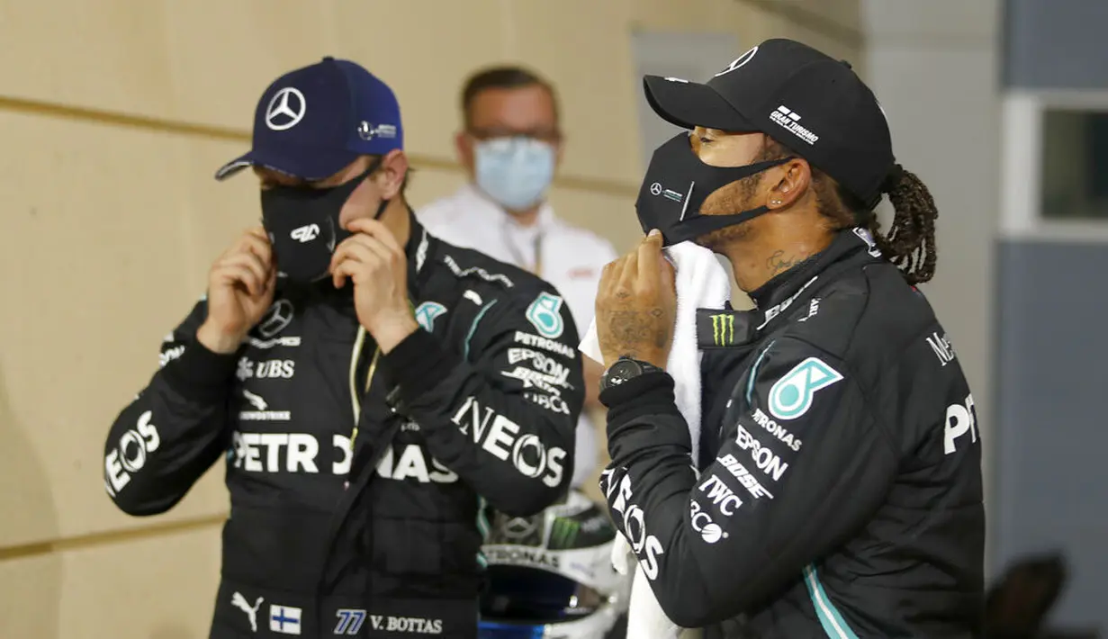 Pembalap Mercedes Lewis Hamilton (kanan), dan pembalap Mercedes Valtteri Bottas memakai masker usai sesi kualifikasi di Formula 1 Sirkuit Internasional Bahrain di Sakhir, Bahrain, Sabtu (28/11/2020). Lewis Hamilton dinyatakan positif COVID-19. (Hamad Mohammed, Pool via AP, File)