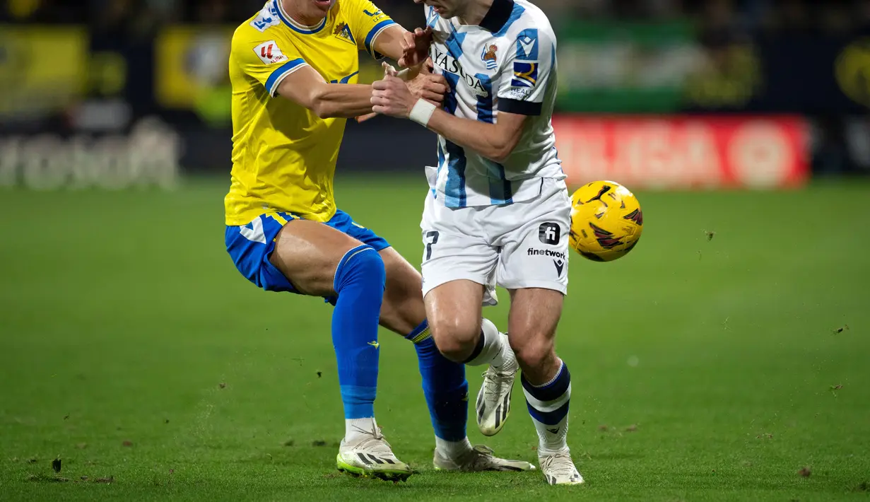 Gelandang Cadiz #11 Ivan Alejo (Kiri) berebut bola dengan bek Real Sociedad #17 Kieran Tierney pada pekan ke-18 Liga Spanyol di stadion Nuevo Mirandilla, Jumat (22/12/2023) dini hari WIB. (JORGE GUERRERO / AFP)