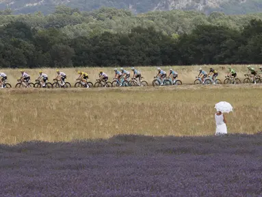 Seorang wanita dengan gaun dan payung putih menonton balapan Tour de France etape ke-19 dengan jarak tempuh 222,5 km dari Embrun menuju Salon-de-Provence, Prancis, (21/7/2017). (AP/Christophe Ena)